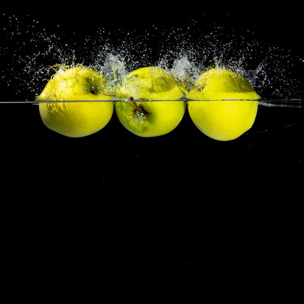 Foto grüner apfel drei mit dem spritzen, das auf den wasserrand schwimmt