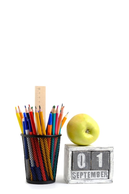 Foto grüner apfel-organizer mit bleistiften und lineal, schreibwarenständer und kalender mit datum 01. september auf weißem hintergrund