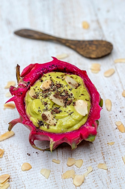 Grüner Avocado-Smoothie in Drachenfruchthaut mit Mandelflocken und Chiasamen zum Frühstück, Nahaufnahme. Das Konzept der gesunden Ernährung, Superfood. Bali, Indonesien