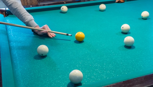 Grüner Billardtisch mit weißen Kugeln. Junger Mann spielt Billard