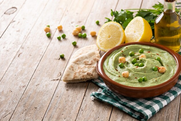 Grüner Erbsen-Hummus und Fladenbrot auf Holztisch