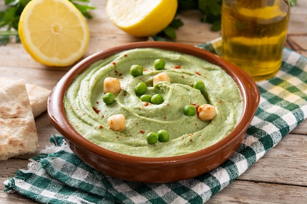 Grüner Erbsenhummus und Fladenbrot auf Holztisch