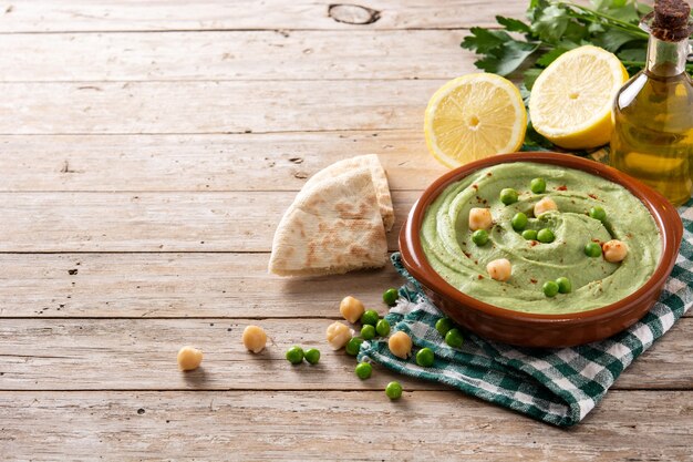 Grüner Erbsenhummus und Fladenbrot auf Holztisch