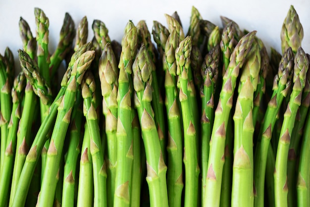 Grüner frischer Spargel auf grauem Hintergrund. Ansicht von oben. Rohes, veganes, vegetarisches und sauberes Essenkonzept.