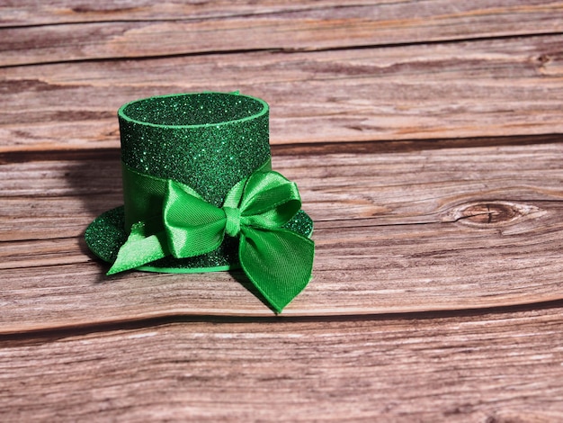 Grüner Hut mit goldenen Münzen und Kleeblatt auf Holztisch, St. Patricks Day-Konzept.