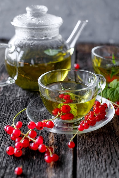 Grüner Kräutertee mit Beeren in der Glasschale auf Holztisch