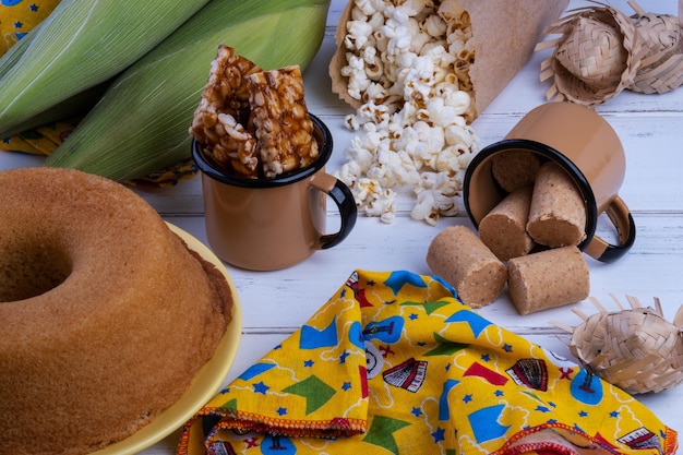 Grüner Mais und Süßigkeiten von festa junina auf weißem Holztisch