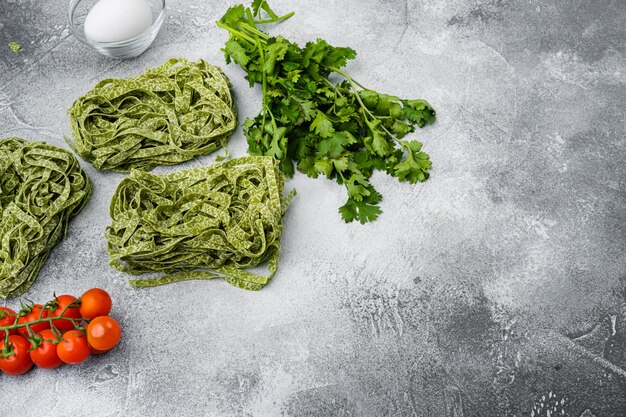 Grüner roher Tagliatelle-Satz, auf grauem Steintischhintergrund, mit Kopienraum für Text