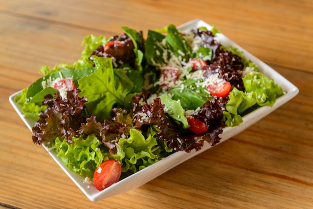 Grüner Salat in weißer Schüssel auf Holztisch