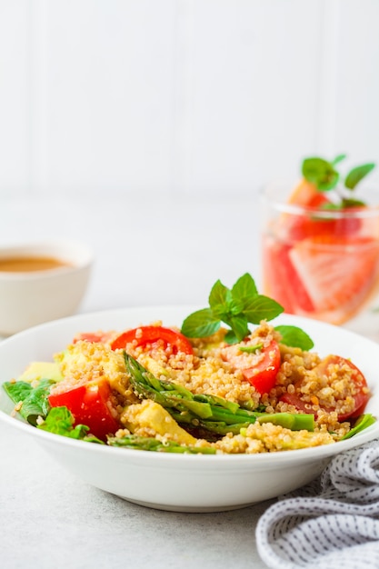 Grüner Salat mit Quinoa, Avocado und Spargel in einer weißen Schüssel.