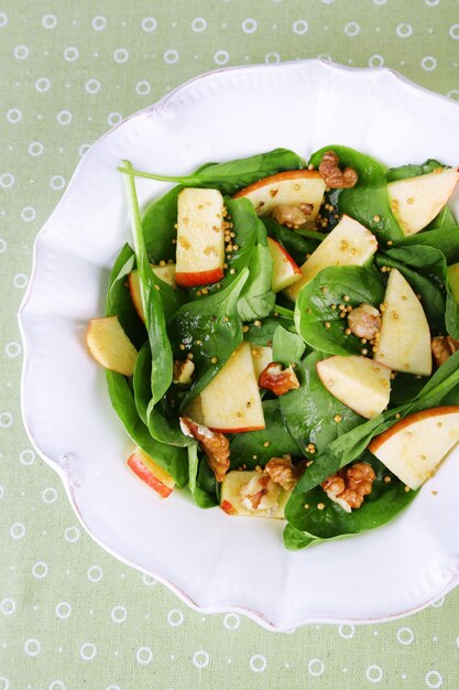 Grüner Salat mit Spinatäpfeln, Walnüssen und Käse auf farbigem Tischdeckenhintergrund