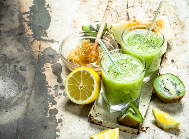 Grüner Smoothie aus Kiwi, Melone und Zitrone mit Honig. Auf rustikalem Hintergrund.