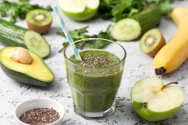 grüner Smoothie im Glas mit Stroh und Früchten