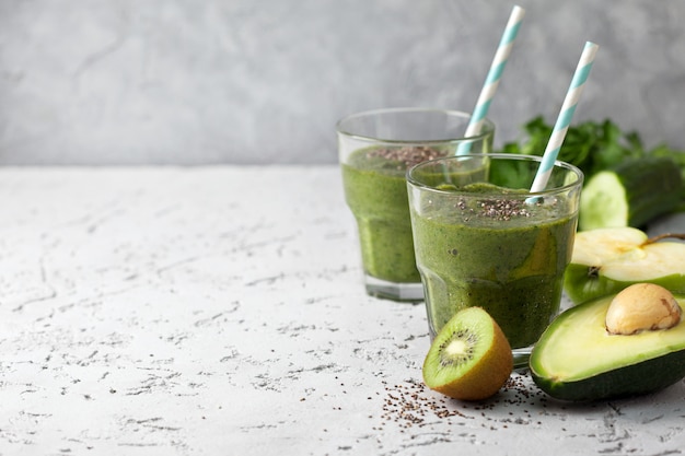 grüner Smoothie im Glas mit Stroh und Früchten