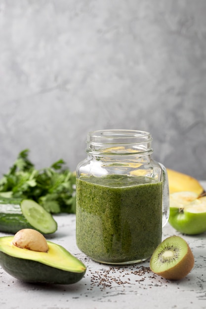 grüner Smoothie im Glas mit Stroh und Früchten