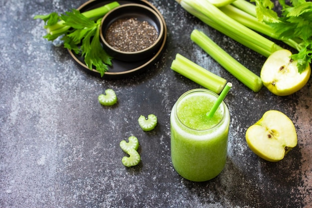 Grüner Smoothie mit Sellerie und Apfel auf einer Arbeitsplatte aus dunklem Stein Kopieren Sie Platz