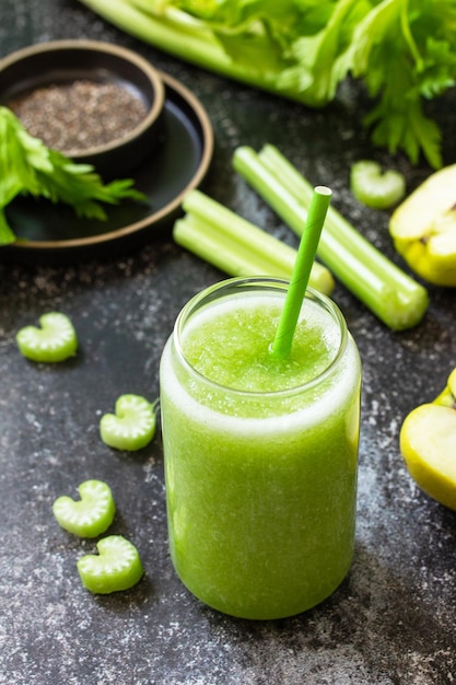 Grüner Smoothie mit Sellerie und Apfel auf einer Arbeitsplatte aus dunklem Stein