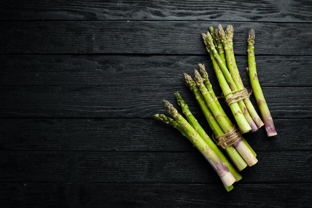 Grüner Spargel Frischer Spargel auf schwarzem Hintergrund Ansicht von oben Freier Platz für Ihren Text