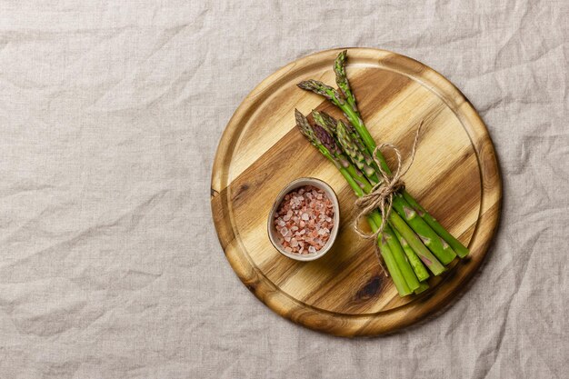 Foto grüner spargel mit rosa salz auf einem holzschnittbrett