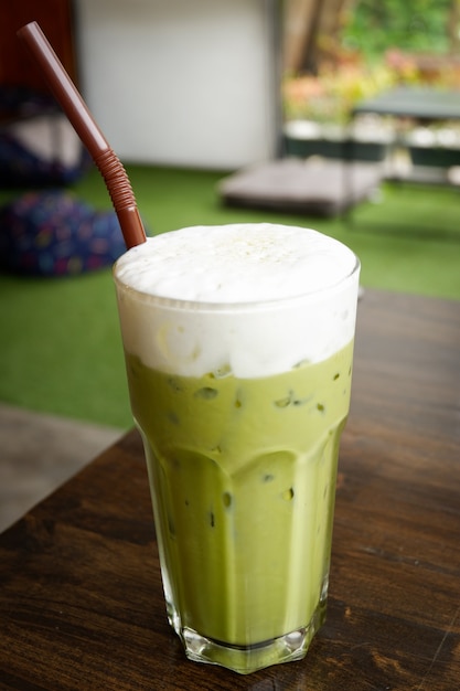 Grüner Tee des Milchschaum-Eises grüner Tee im Glas mit Strohhalm des grünen Tees des Eis matcha auf Tabelle in c