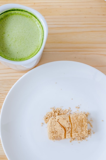 Grüner Tee des Nachtischs und der Milch auf Holztisch