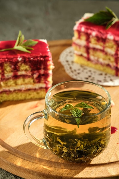 grüner tee in einem transparenten tassenkeks mit himbeeren und creme auf einem holztisch