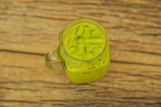 Grüner Tee Latte mit Eis im Einmachglas und Strohhalm auf Holzhintergrund Hausgemachter Iced Matcha Latte Tea mit Milch Zero Waste