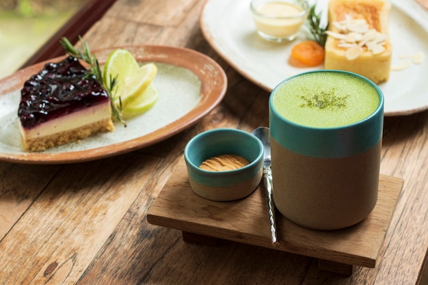 Grüner Tee Matcha in einem Schalen- und Nachtischkuchen auf Tabelle