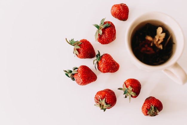 Grüner Tee mit Erdbeeren auf einer weißen Oberfläche Flache Ansicht von oben