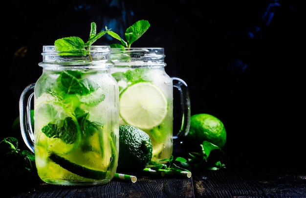 Grüner Tee mit selektivem Fokus des schwarzen Hintergrundes der Minze und des Eises