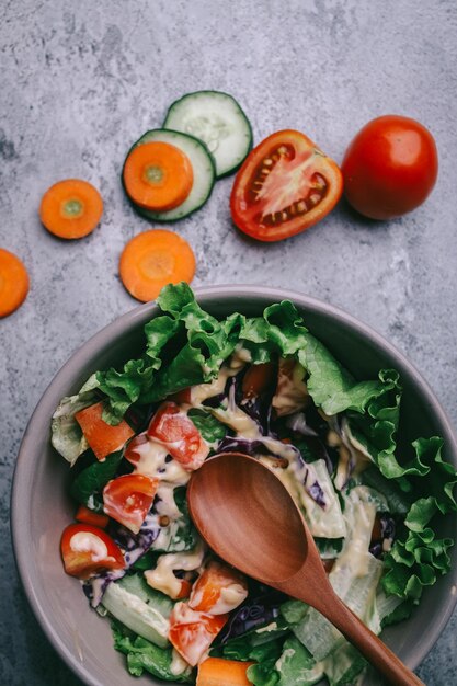 Grüner veganer Salat aus grüner Blättermischung und Gemüse Draufsicht auf grauem Steintisch