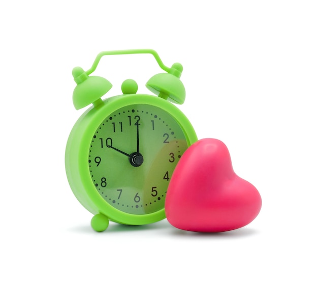 Grüner Wecker mit rosa Herz auf Weiß mit Kopienraum Zeit für Liebe und ein gesundes Konzept
