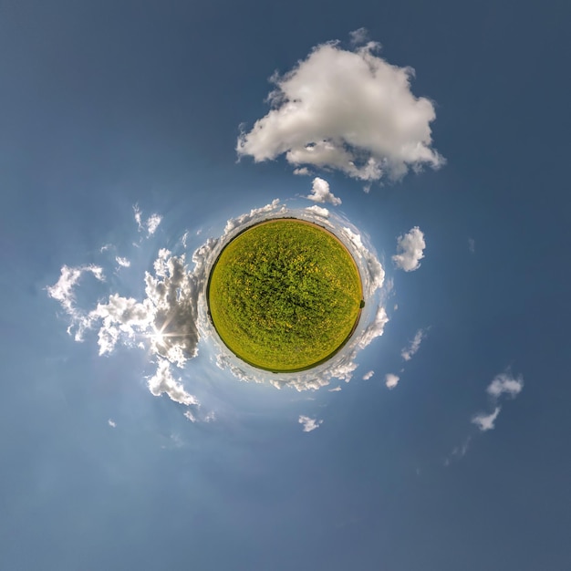 Grüner winziger Planet am blauen Himmel mit schönen Wolken mit Transformation des sphärischen Panoramas 360 Grad Krümmung des Raums