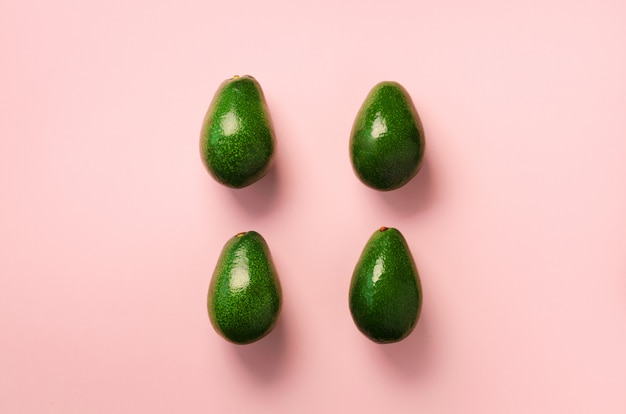 Grünes Avocadomuster auf rosa Hintergrund. Bio-Avocados in minimaler Flachlage.