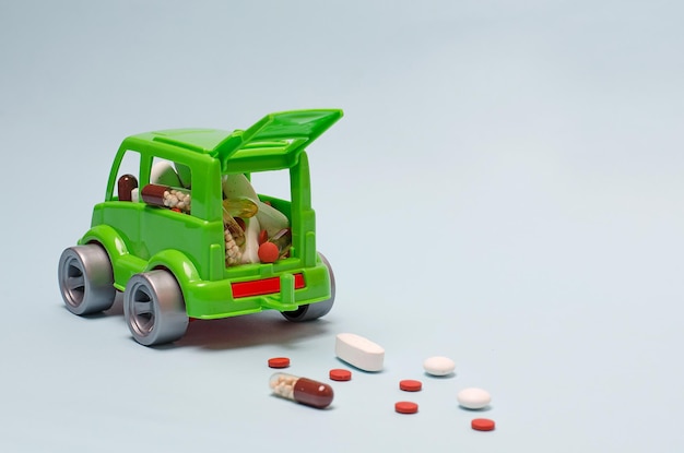 Grünes Babyauto gefüllt mit Pillen, Vitaminen, Medikamenten