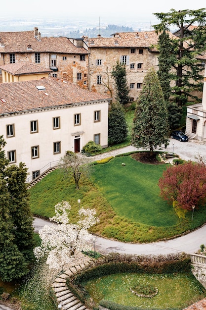 Grünes Blumenbeet mit Bäumen im Innenhof eines alten Hauses in Bergamo Draufsicht