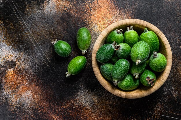 Grünes feijoa trägt in einer hölzernen Platte auf einem dunklen Hintergrund Früchte. Tropische Früchte Feijoa. Ansicht von oben