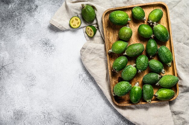 Grünes feijoa trägt in einer hölzernen Platte auf einem grauen Hintergrund Früchte. Tropische Früchte Feijoa. Ansicht von oben