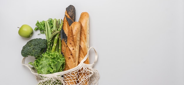 Grünes Gemüse Obst und Brot Baguette im Netzbeutel auf weißem Hintergrund, Ansicht von oben