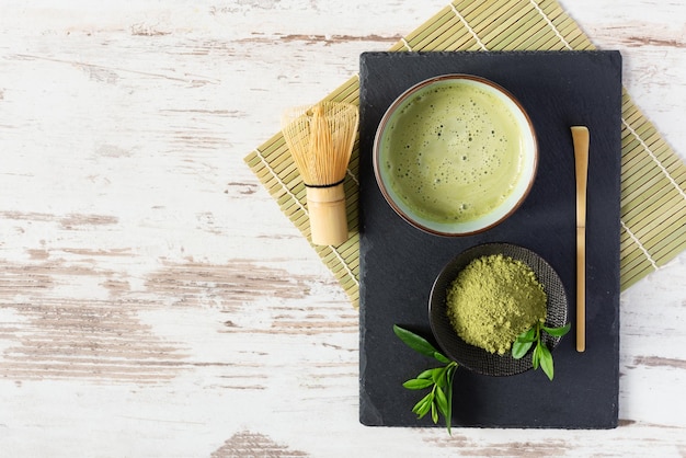 Grünes Matcha-Teegetränk und Teezubehör auf dem schwarzen Brett Japanische Teezeremonie
