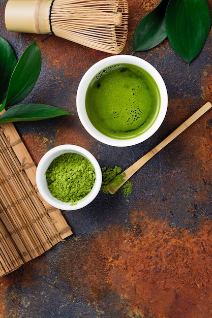 Grünes matcha Teegetränk und Teezubehör auf dunklem rostigem