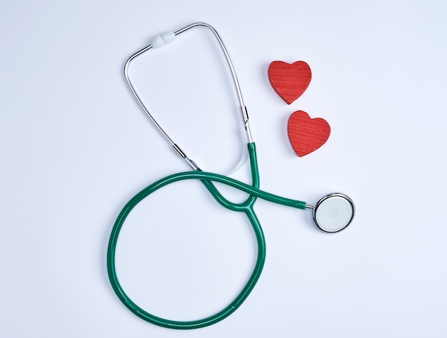 Grünes medizinisches Stethoskop und zwei rote hölzerne Herzen