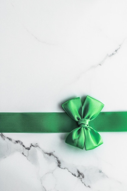 Grünes Seidenband und Schleife auf Marmorhintergrund St. Patricks Day Geschenk oder Weihnachts-Glamour-Geschenkdekor für luxuriöse digitale Markenferien-Flatlay-Design