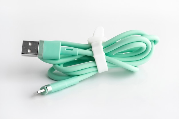 Grünes USB-Kabel zum Aufladen eines Mobiltelefons auf weißem Hintergrund. Handyzubehör aus Silikon