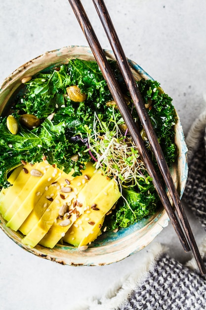 Grünkohlsalat mit Avocado und Sprossen in einer Schüssel, gesundes veganes Lebensmittelkonzept,