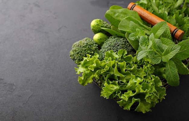 Grüns: Spinat, Gurke, Broccoli, Knoblauch, Minze, Petersilie, Salat, Zwiebel auf schwarzem Hintergrund