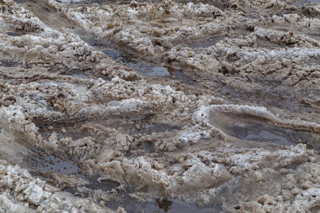 Gruesa capa de nieve húmeda sucia con huellas de ruedas de coche en la calle de invierno fondo de fotograma completo