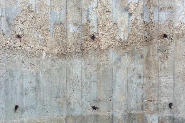 Una gruesa pared exterior de hormigón gris rugoso con huellas visibles de tablones de madera