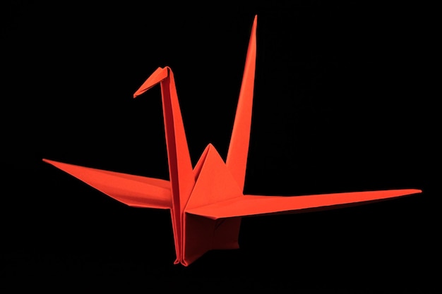 Grulla de origami rojo sobre fondo negro