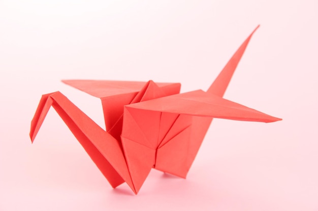 Grulla de origami sobre fondo rosa